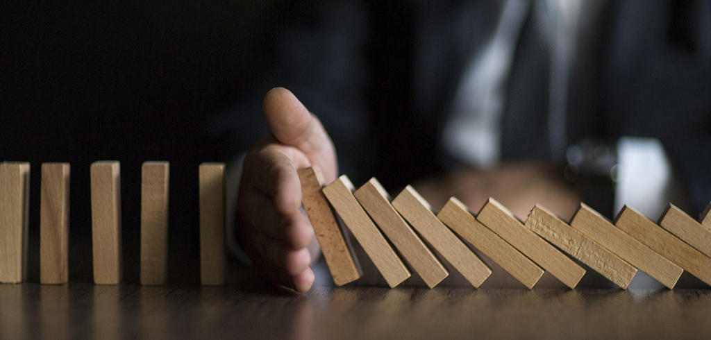 Hand stopping falling dominoes