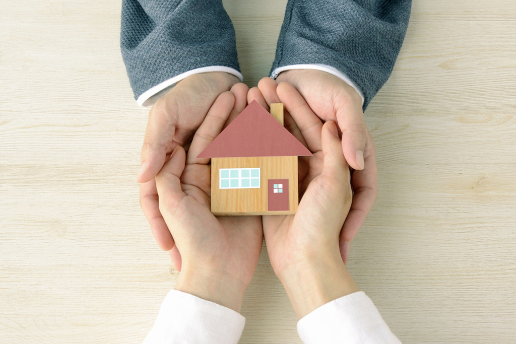 Hands holding small house